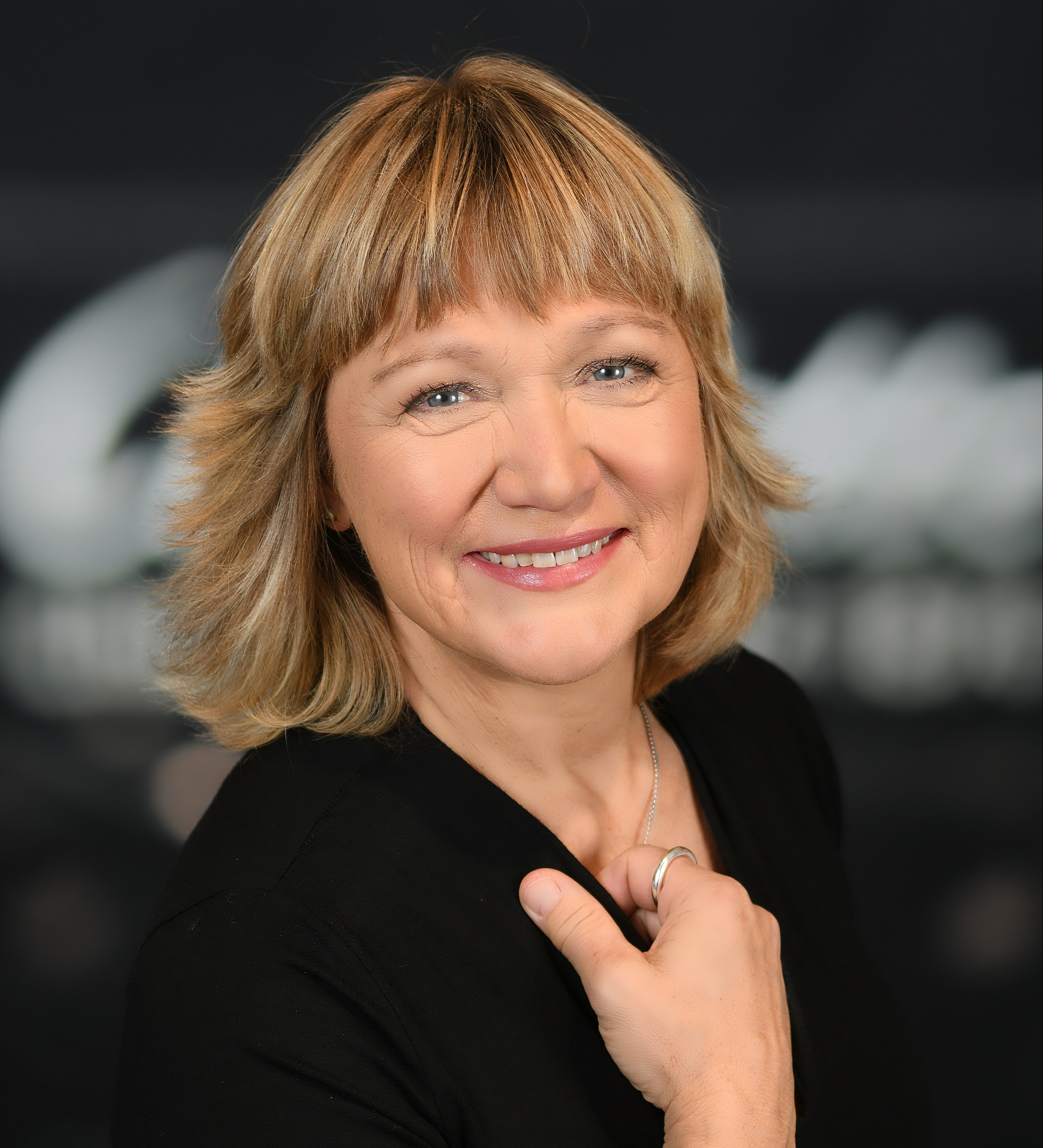 Foto von Marion Thomas, Kopf und Oberkörper, blonde Frau mit schulterlangem Haar lächelt freundlich in die Kamera.